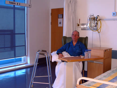 A patient sitting in a hospital ward bedroom