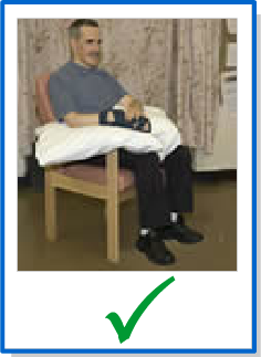 patient sitting comfortably and properly in chair with pillow in lap to support arms